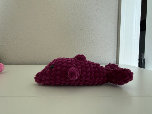 Purple crochet dolphin on a white surface with a neutral background