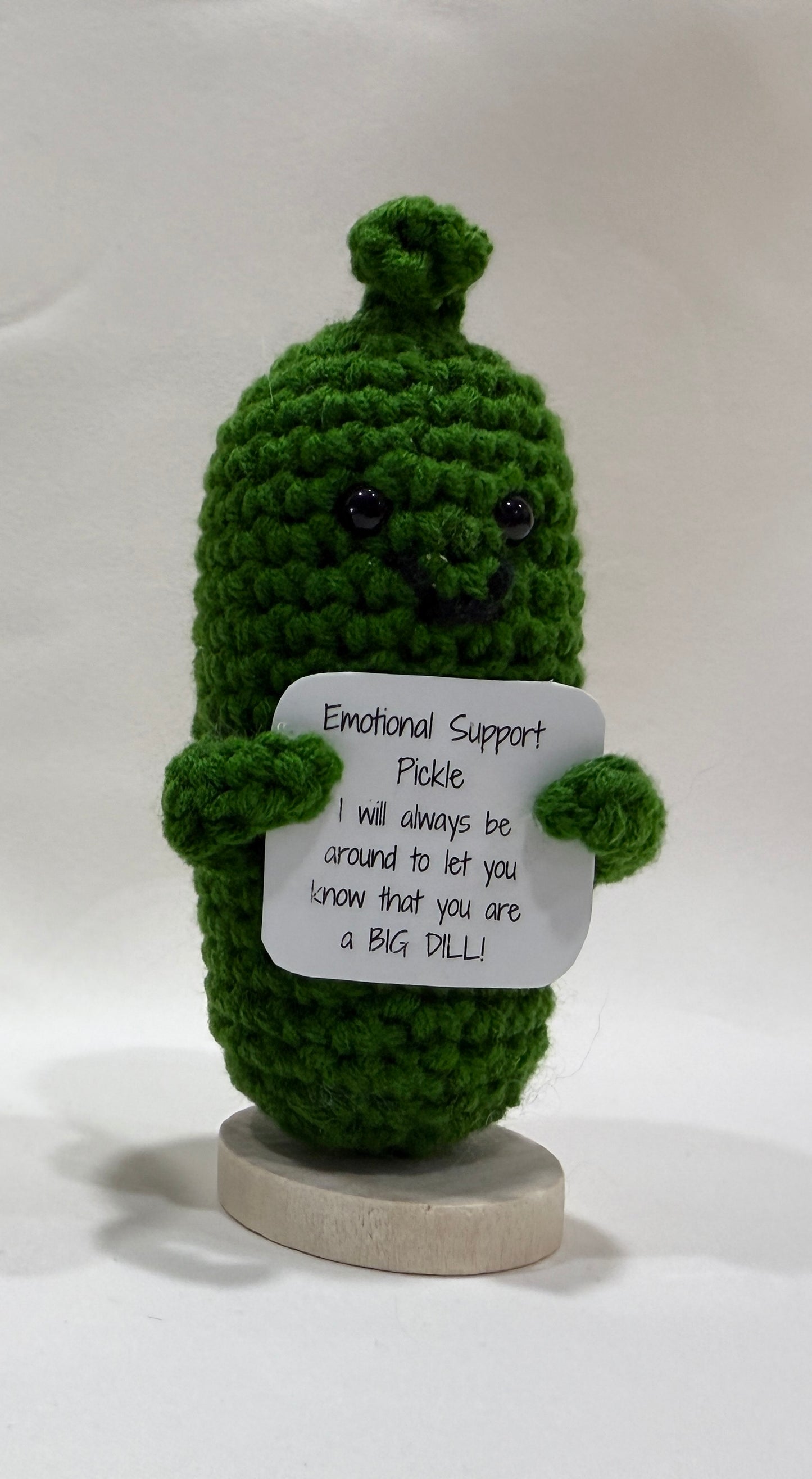 Green crochet pickle with a sign on a white background