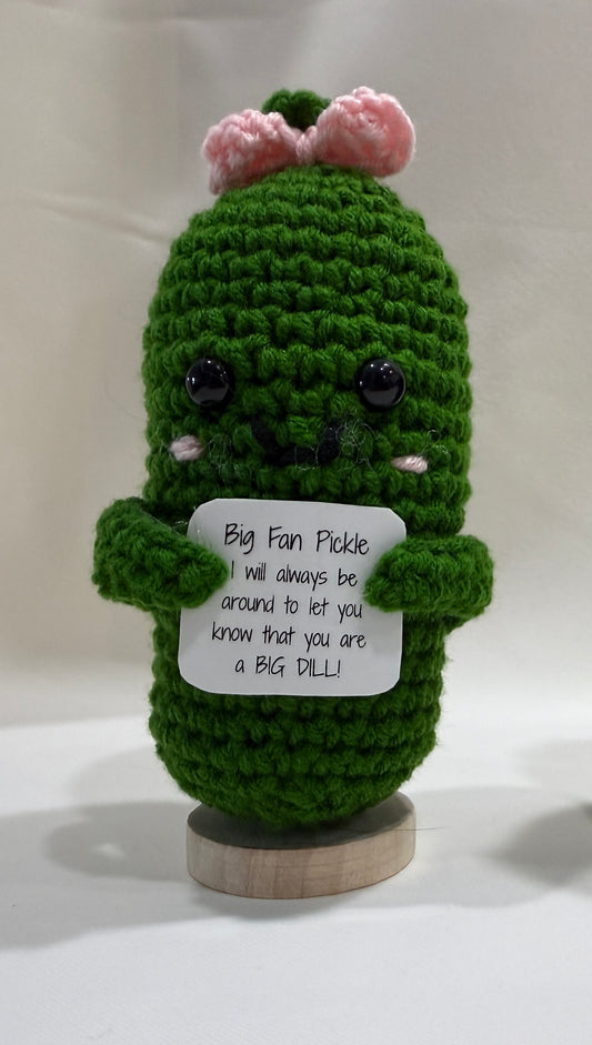 Green crochet pickle with a sign on a white background