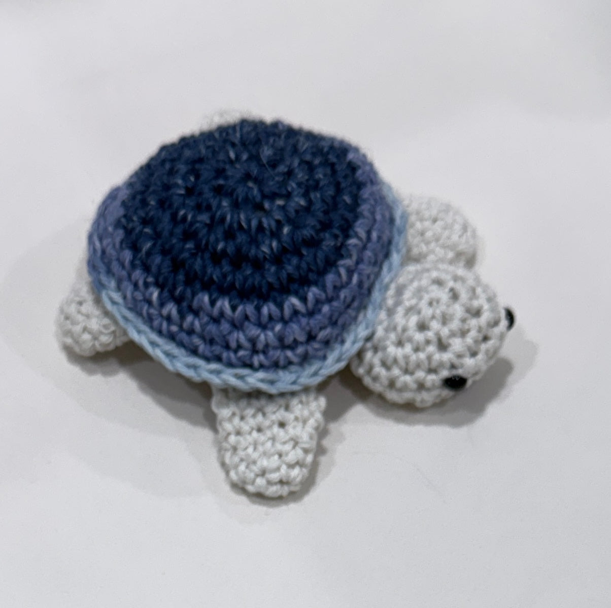 Crocheted turtle with blue shell on a white background