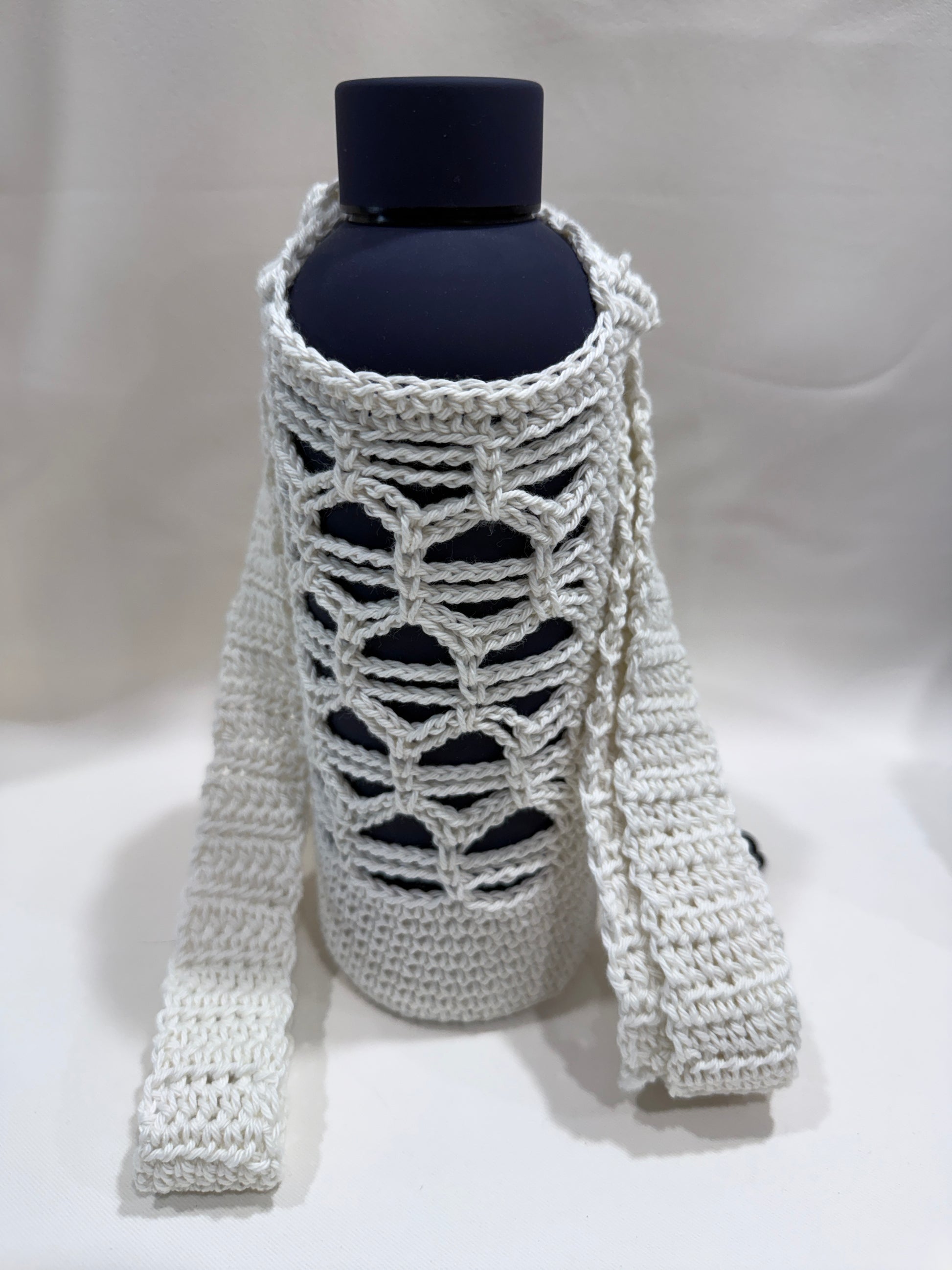 White crochet bottle cover on a blue bottle against a white background