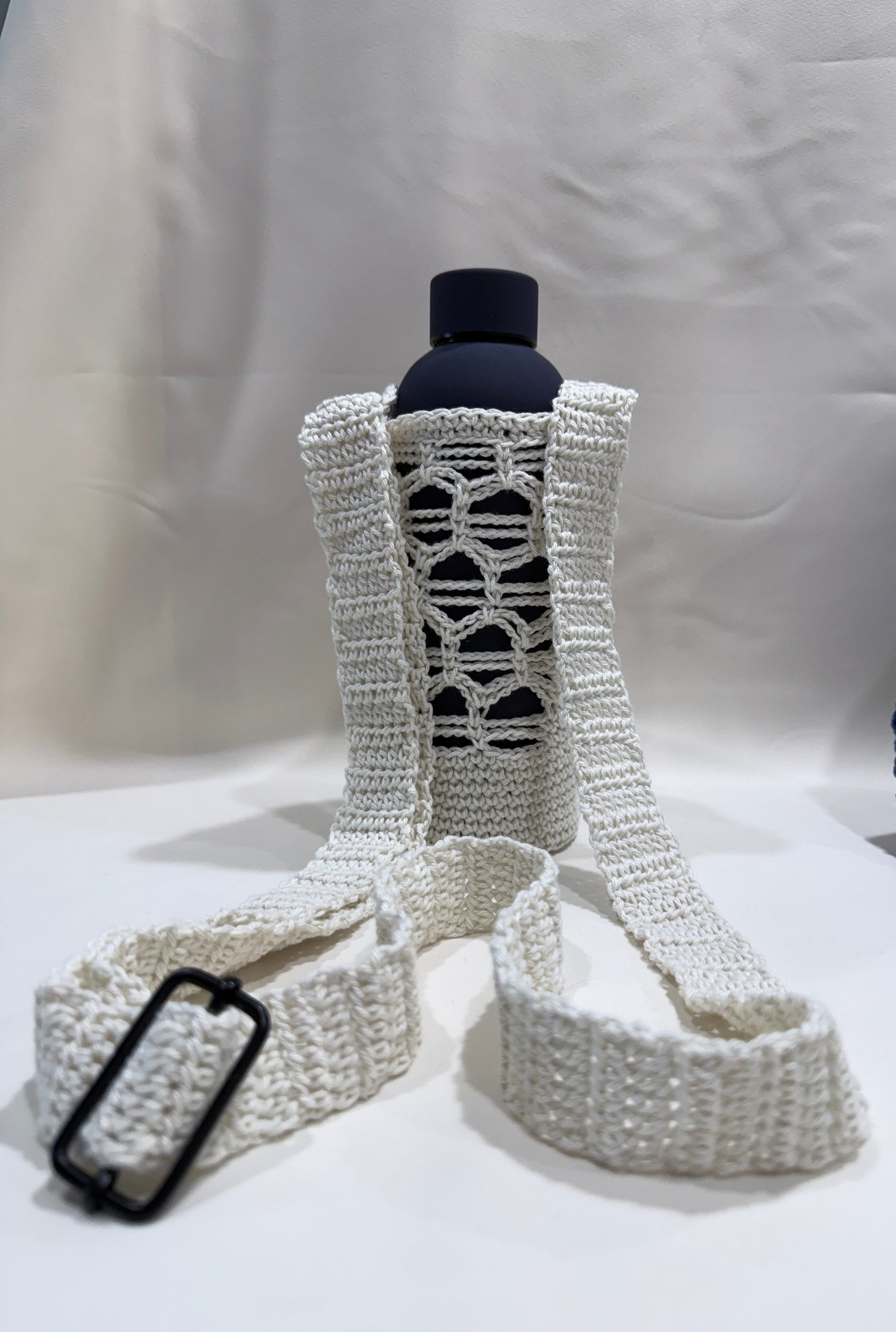 White crocheted bottle cover with blue bottle on a white background