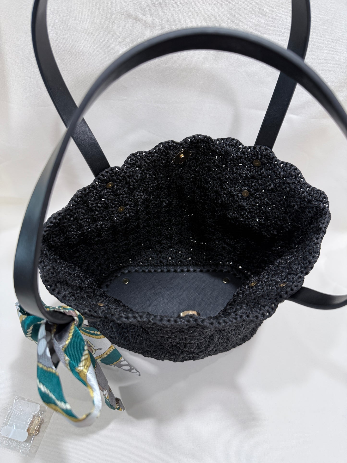 Black crochet handbag interior with a scarf on a light gray background