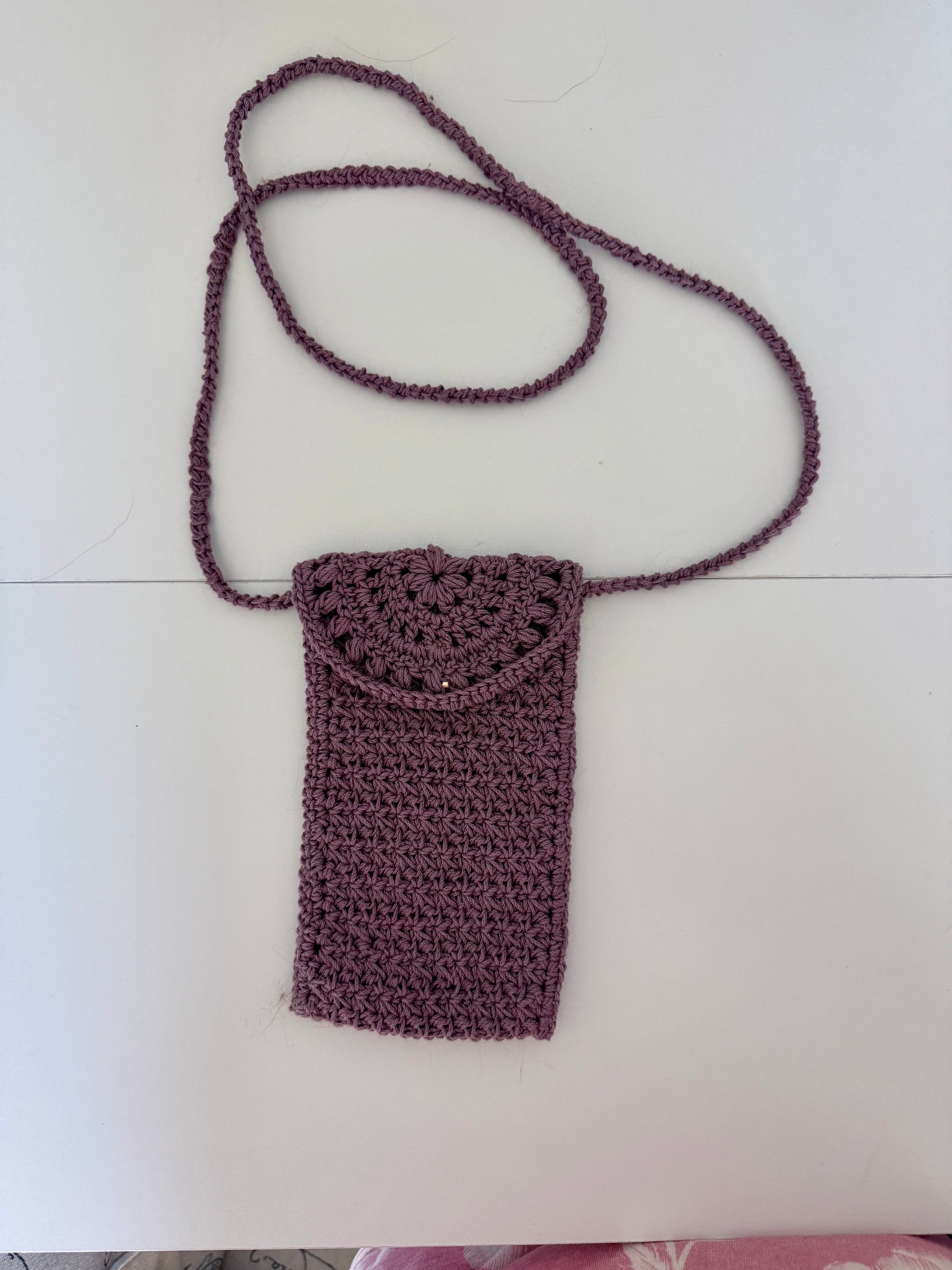 Crocheted Dusty Rose phone carrier with a strap on a white background