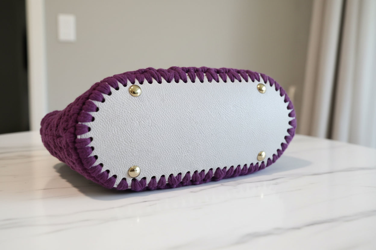 Bottom view of plum crochet purse on a light surface