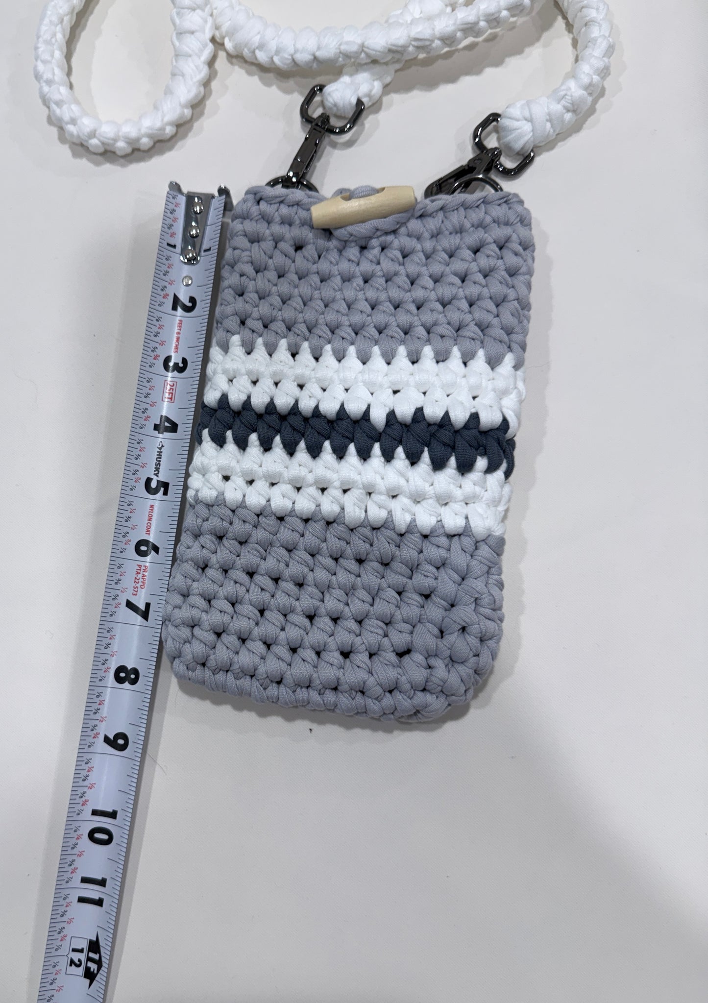 Crocheted pouch with striped pattern next to a ruler on a white background