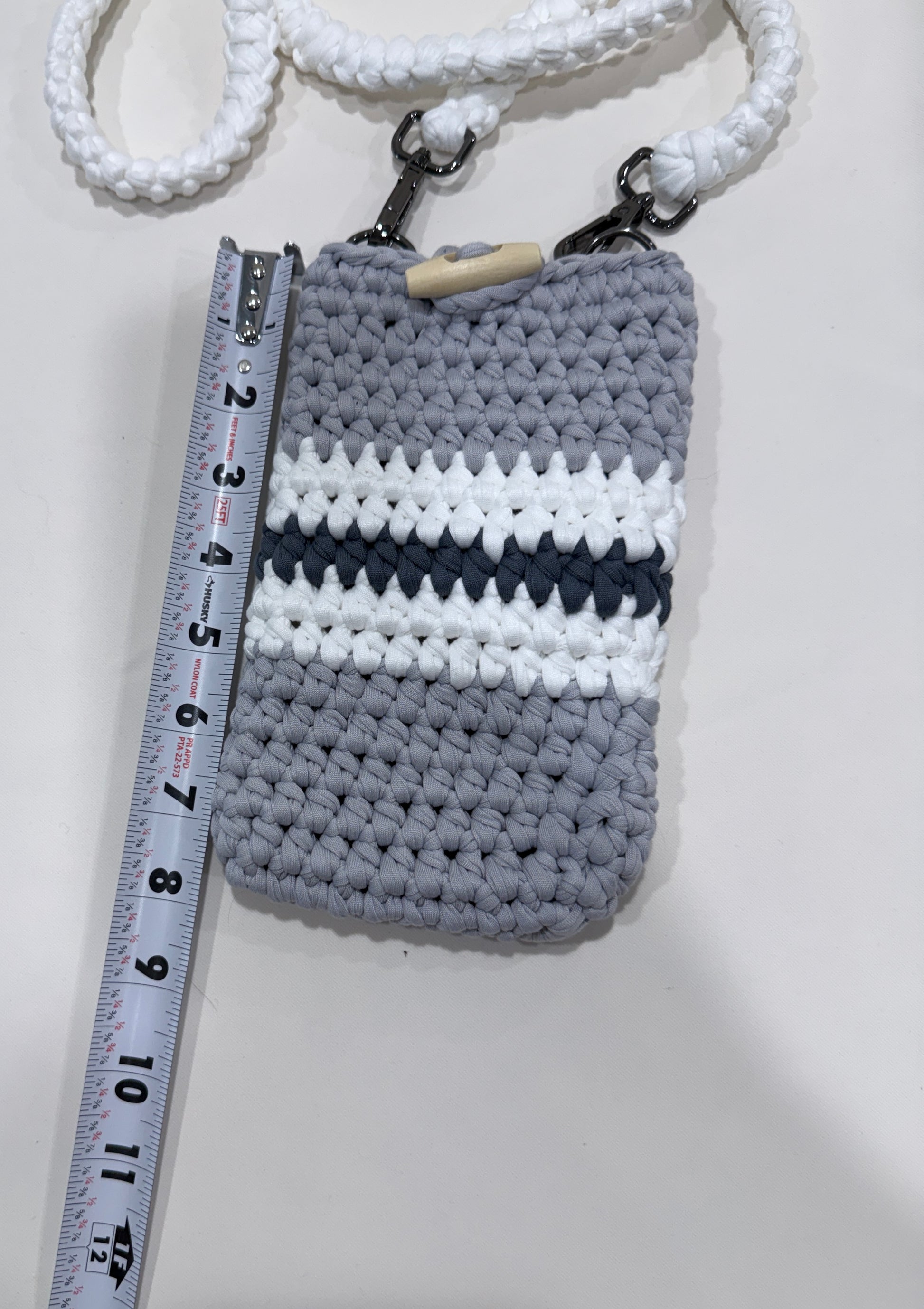 Crocheted pouch with striped pattern next to a ruler on a white background