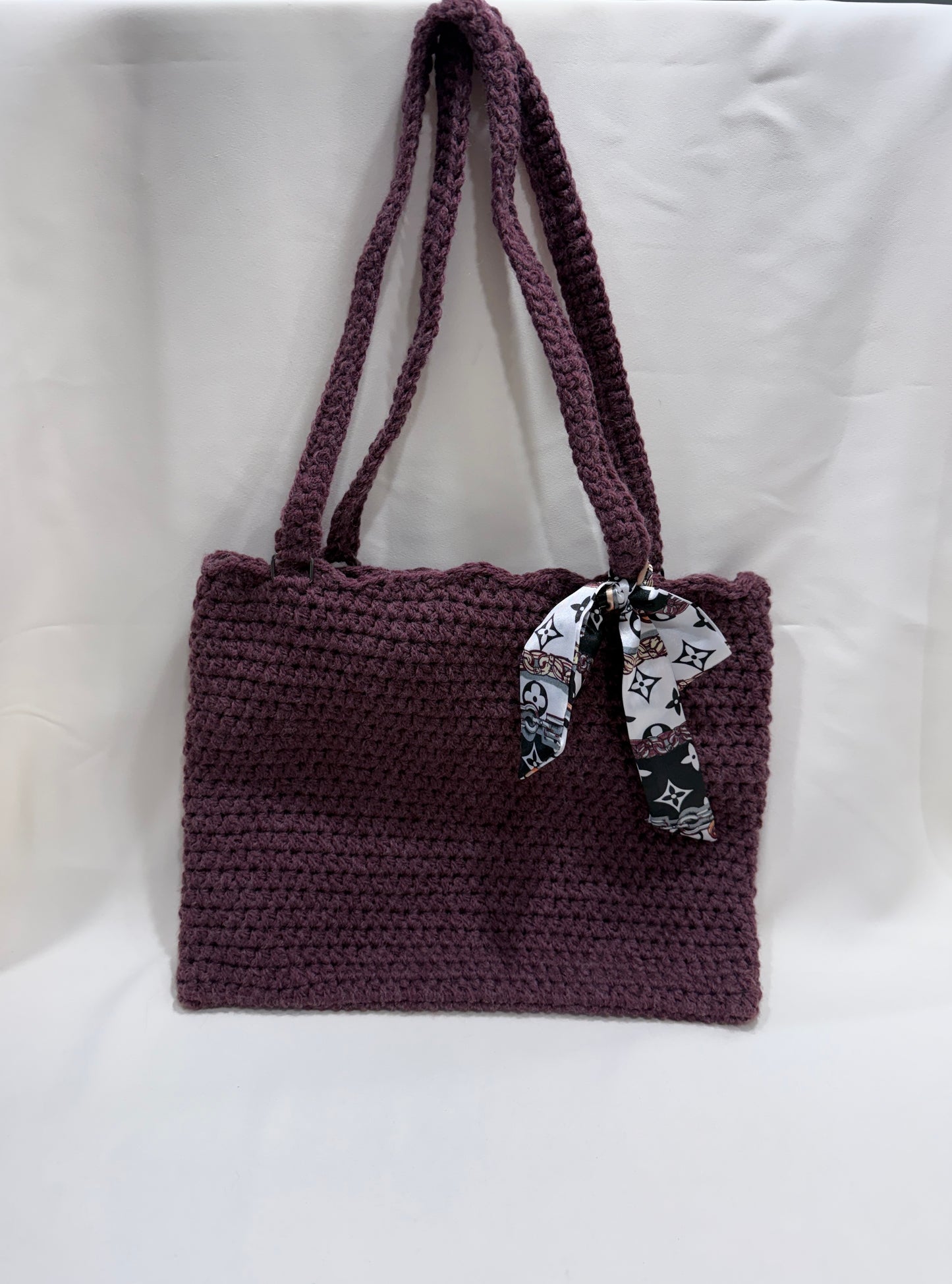 Wine crocheted handbag with a decorative scarf on a white background