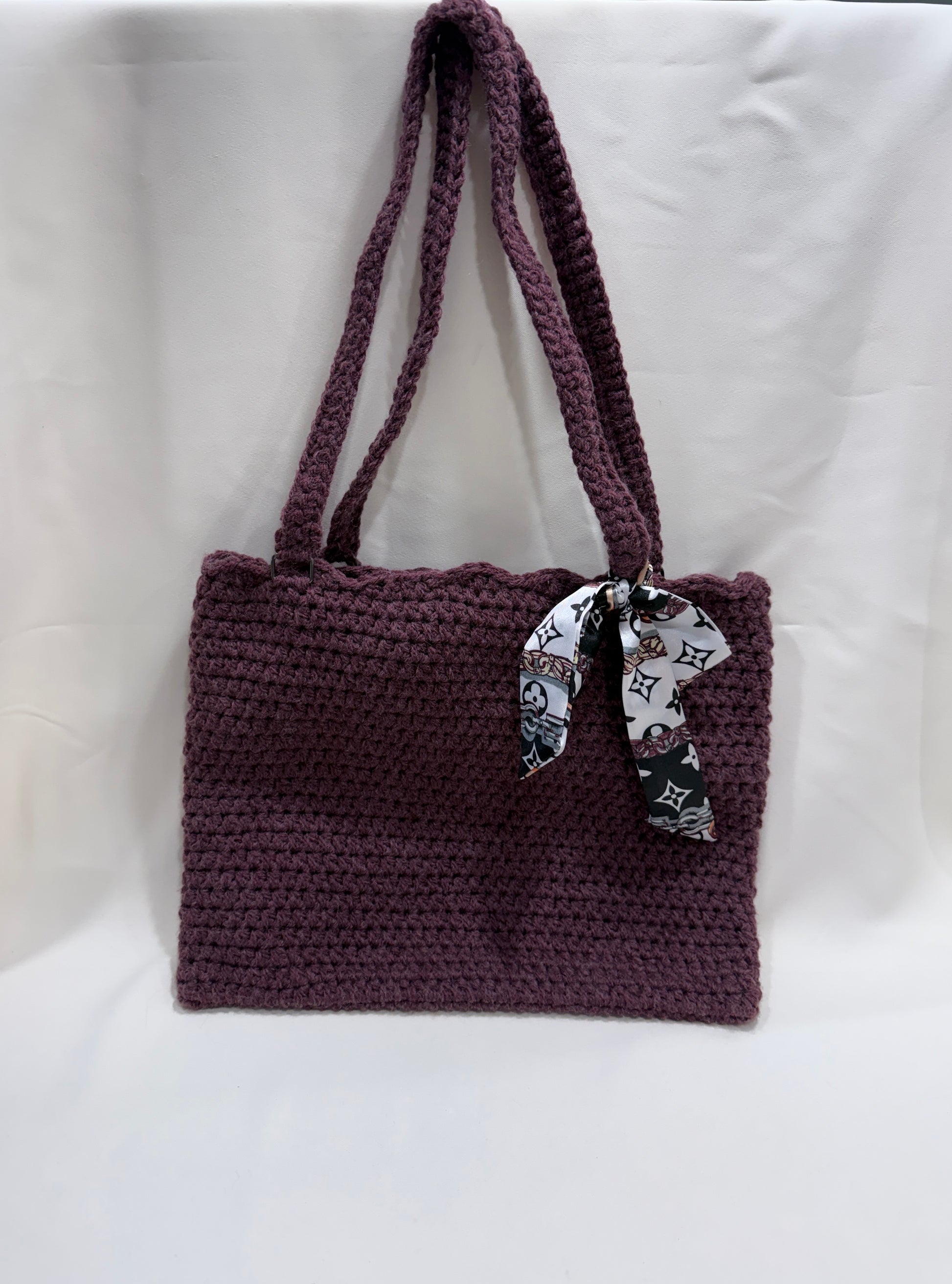 Wine crocheted handbag with a decorative scarf on a white background
