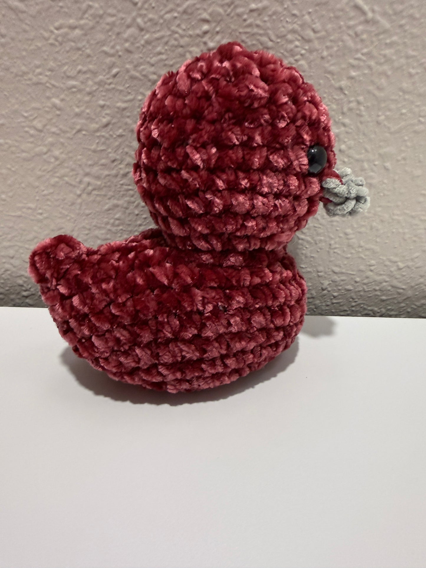 Red textured decorative duck against a wall 