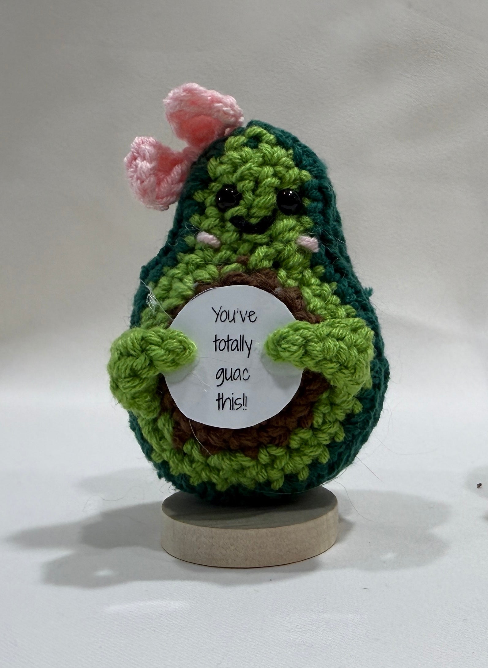 Crocheted avocado with a bow and an encouragement message on a white background