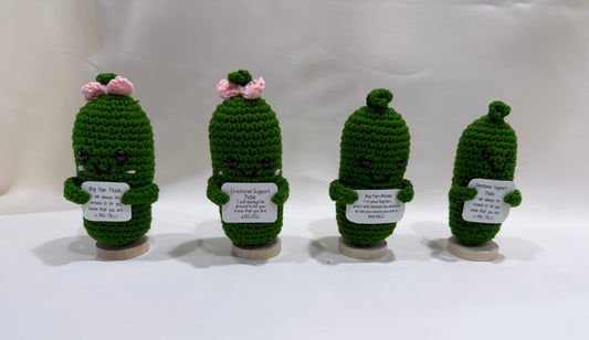 Four green pickles holding encouragement signs on a white background