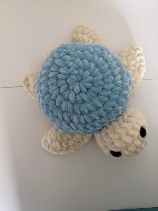 Crocheted turtle with a blue shell on a white background