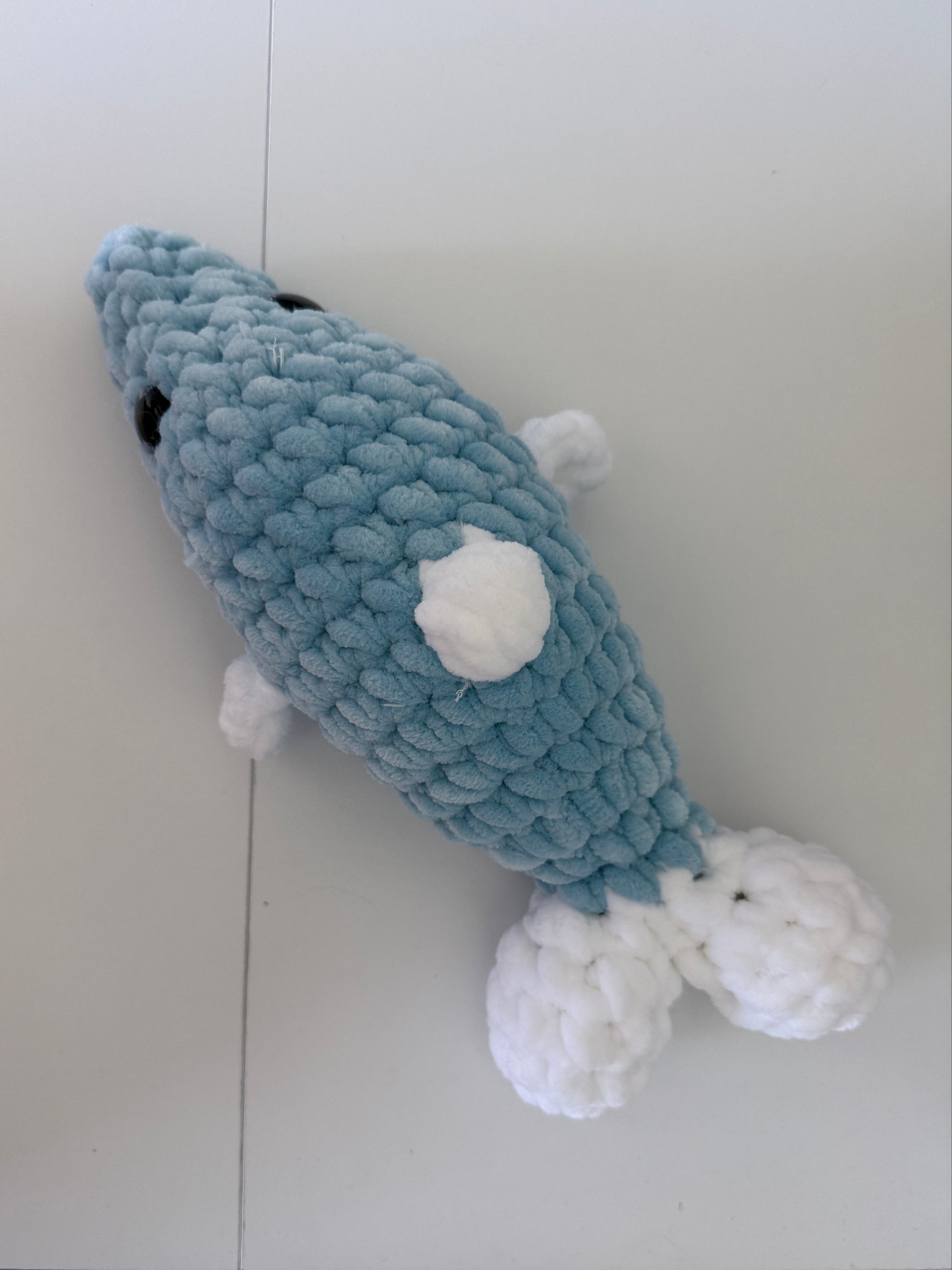 Blue and white crochet dolphin on a white background