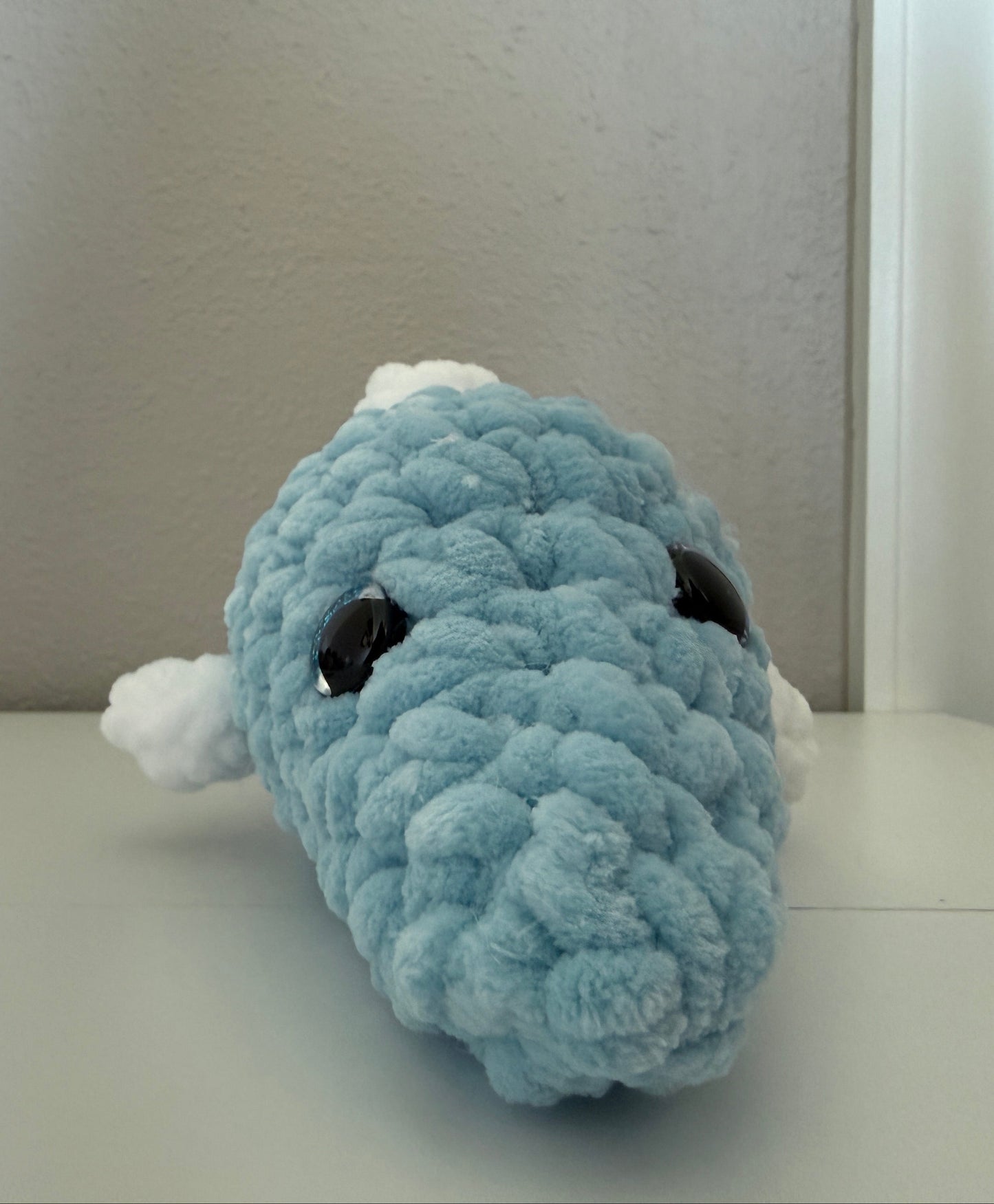 Blue crochet plush dolphin on a white surface