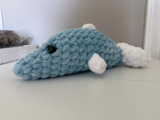 Blue crochet dolphin with white fins on a white surface