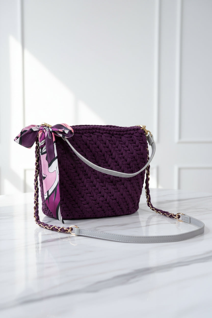 Plum crochet handbag with a patterned strap on a white background