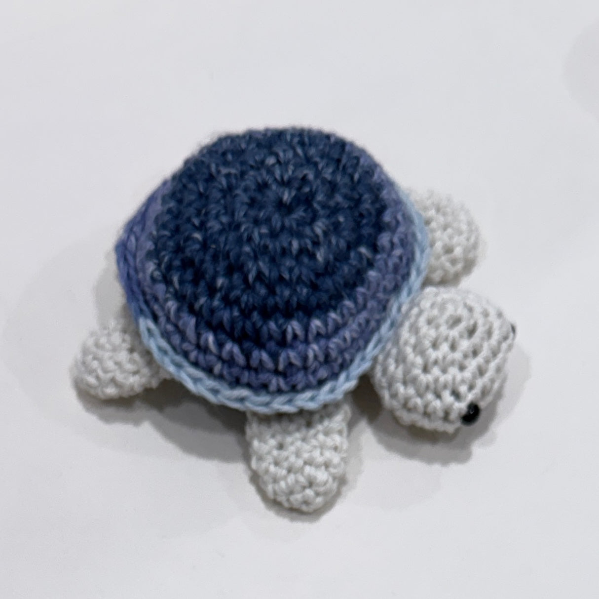 Crocheted turtle with blue shell on a white background