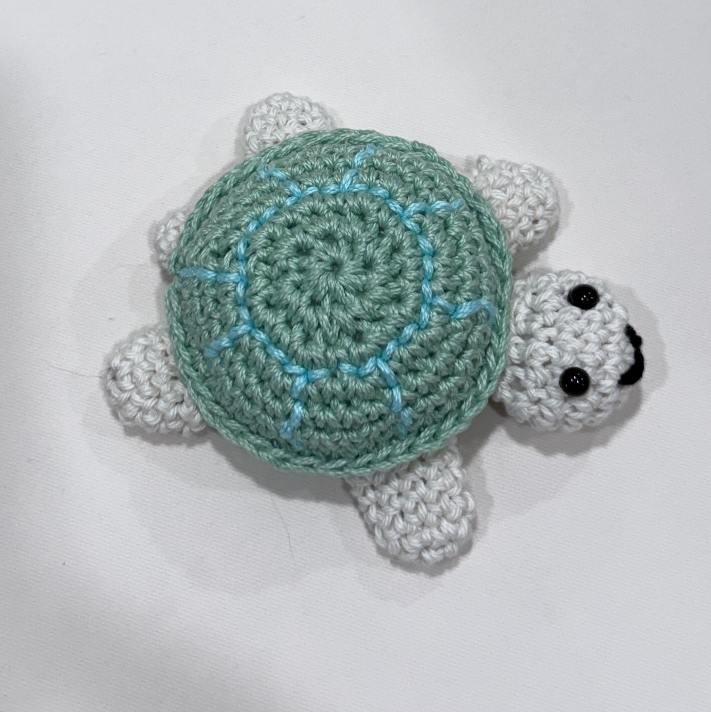 Crocheted turtle with a green accented shell on a white background