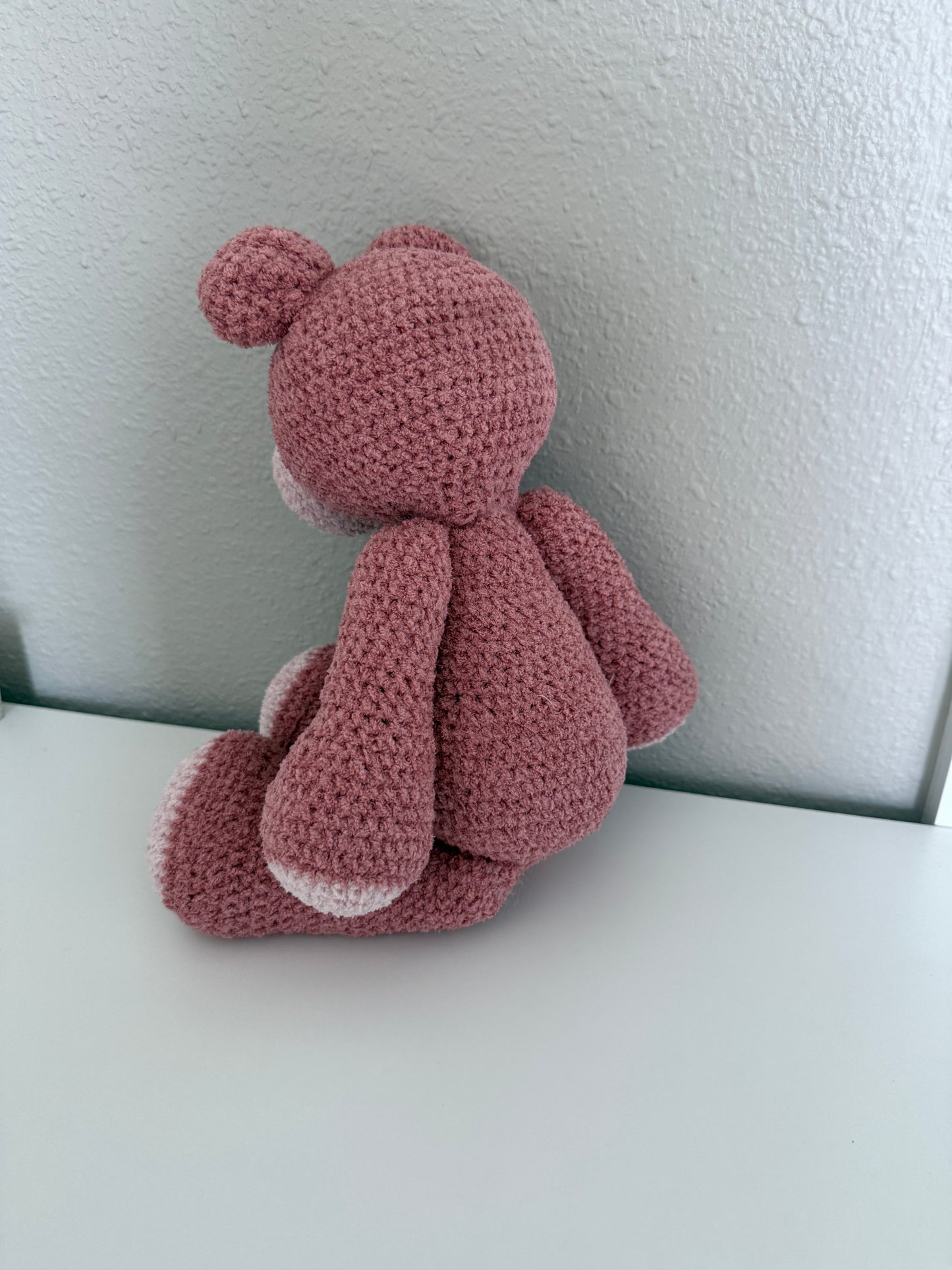 Pink crochet teddy bear on a white background
