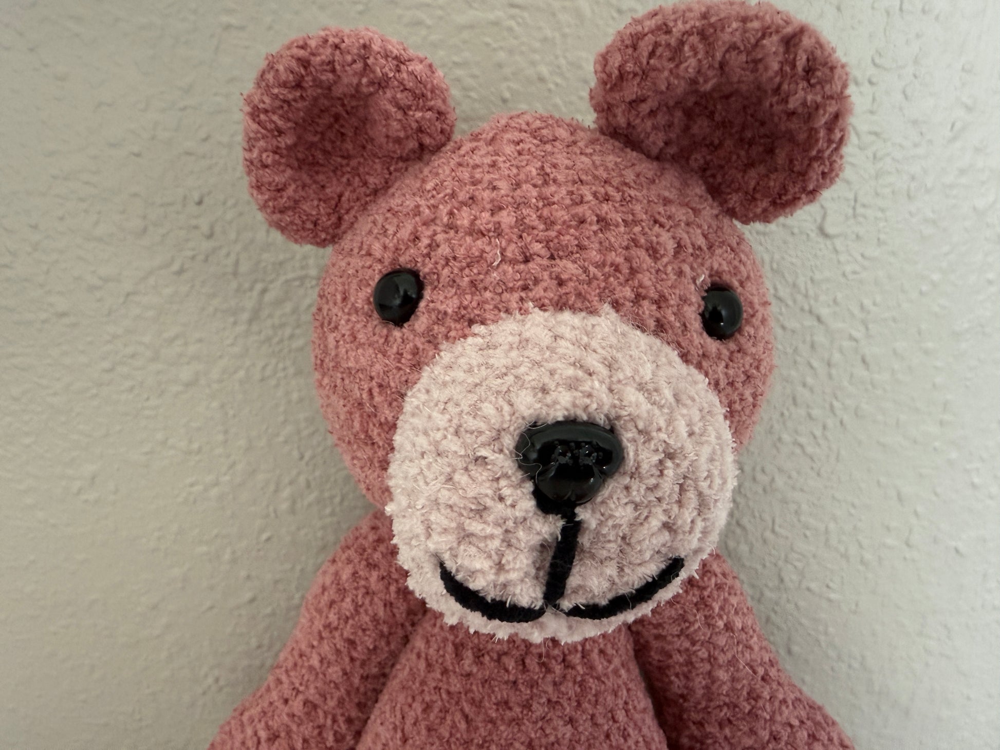 Crocheted teddy bear head with a plain background