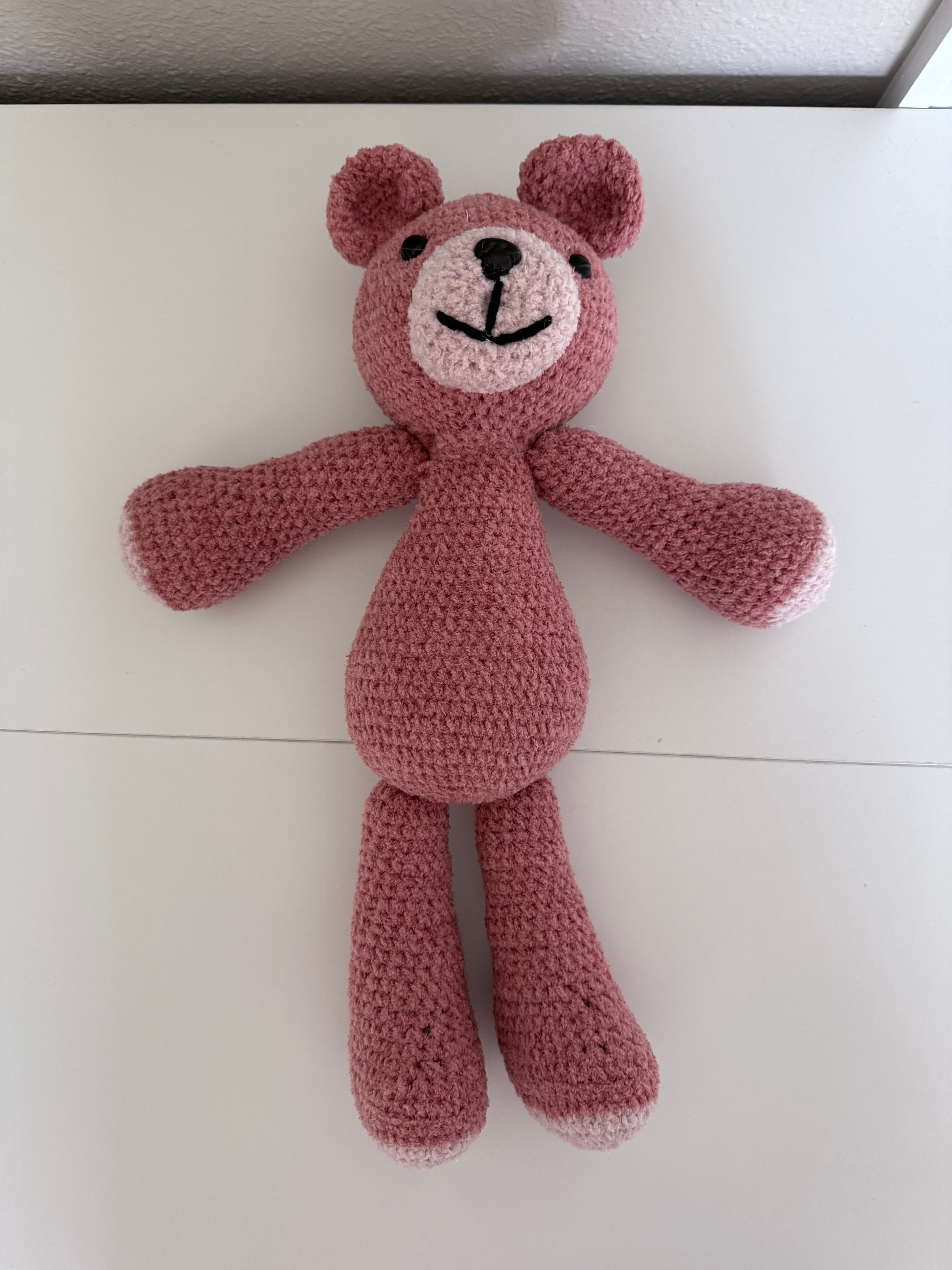 Crochet Pink teddy bear toy on a light-colored table